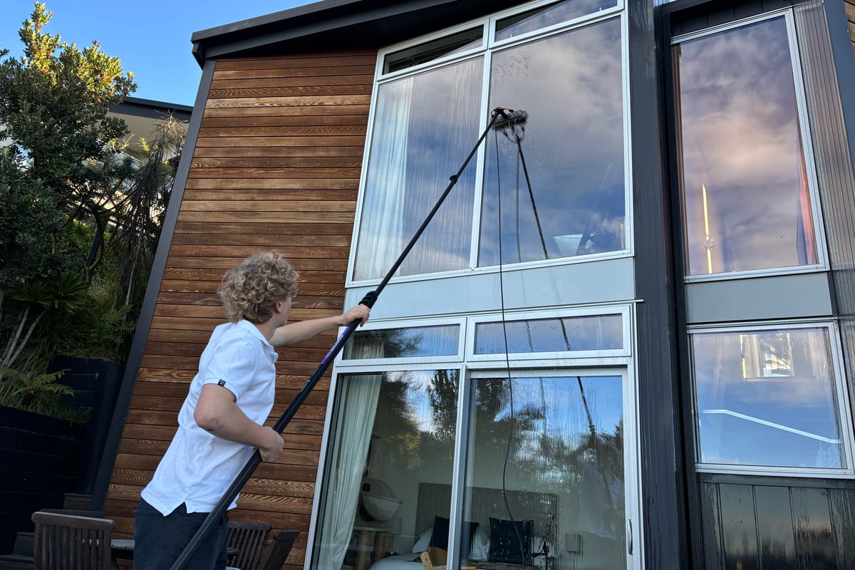 Luca cleaning an upstairs window from the ground with an extendable water-fed pole